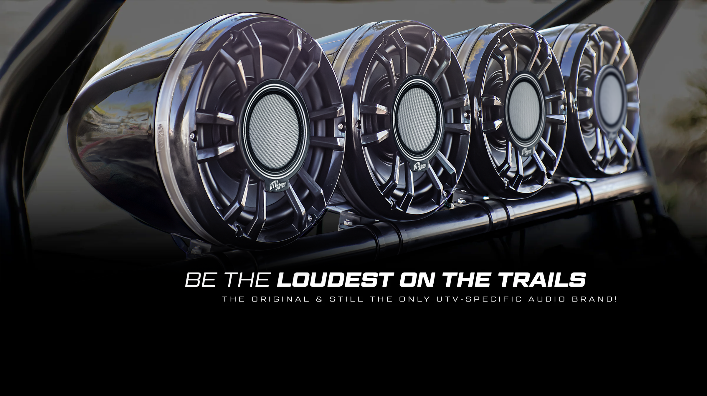 Row of metallic speakers with branding text in the foreground.